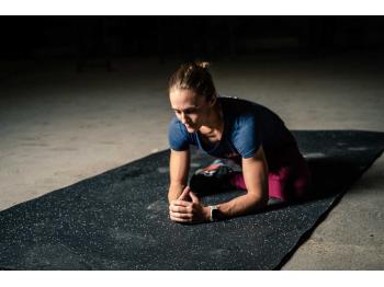 Femme en position d'étirements sur tapis de sol noir - LEVEL addict