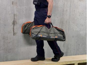 Sandbag de 20 kg avec poignée centrale porté sur la banc traversé par un pompier - LEVEL addict